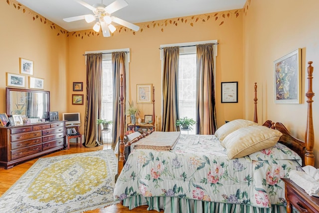 bedroom with access to exterior, light wood-style flooring, multiple windows, and ceiling fan