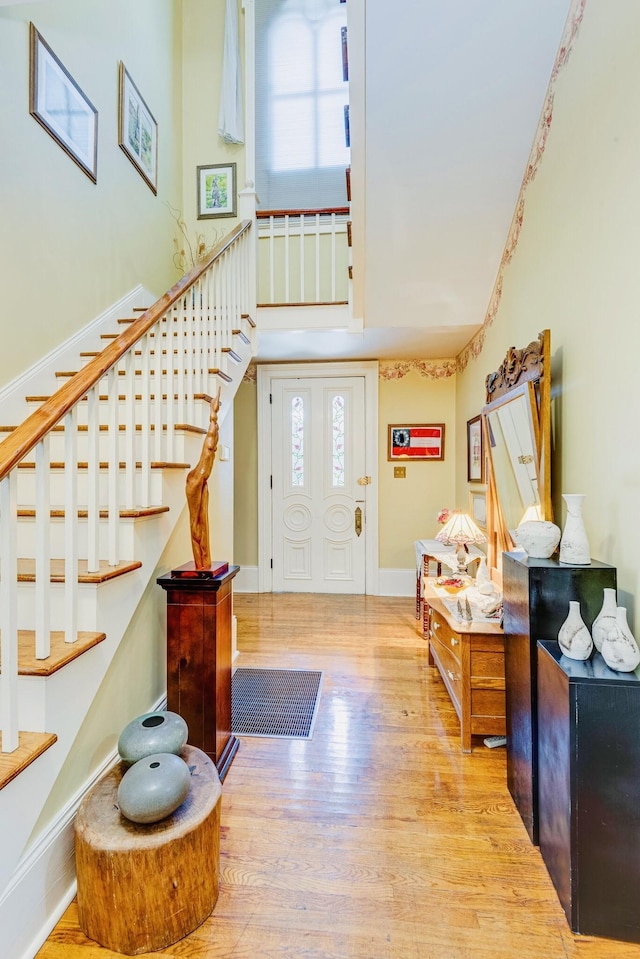 foyer entrance with baseboards, plenty of natural light, wood finished floors, and stairs