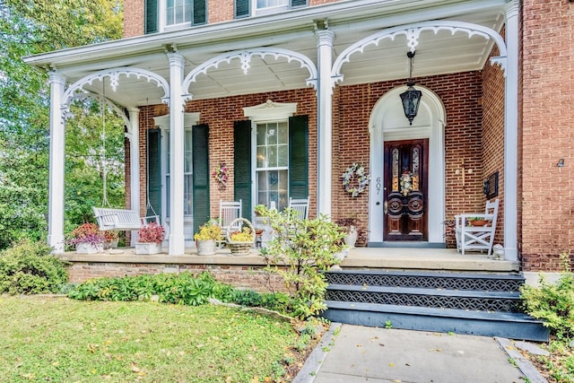 doorway to property featuring brick siding and covered porch