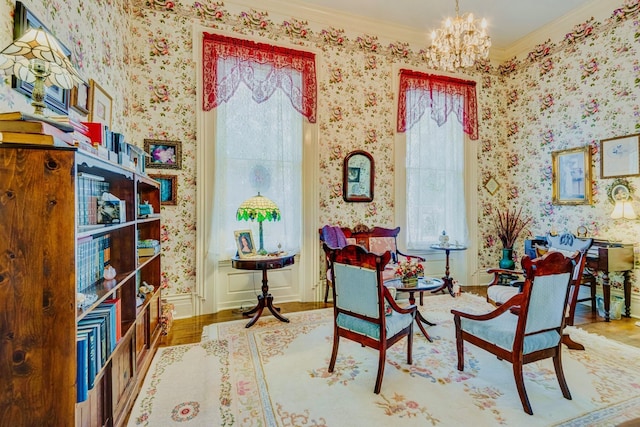 living area featuring wallpapered walls, an inviting chandelier, wood finished floors, and ornamental molding