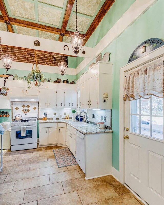 kitchen featuring under cabinet range hood, a sink, backsplash, white appliances, and a chandelier