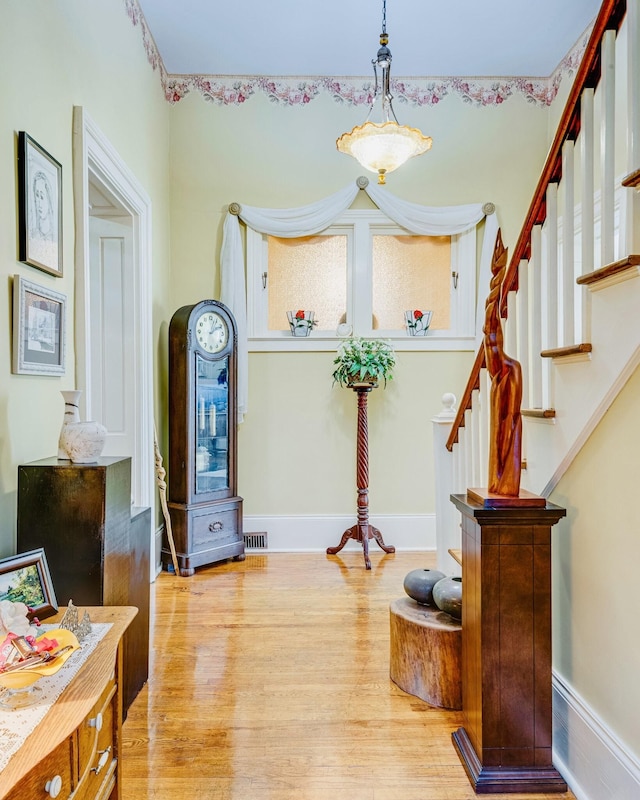 foyer entrance with stairway, baseboards, visible vents, and wood finished floors