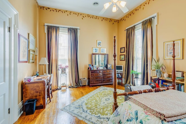 bedroom with wood finished floors, visible vents, and ceiling fan