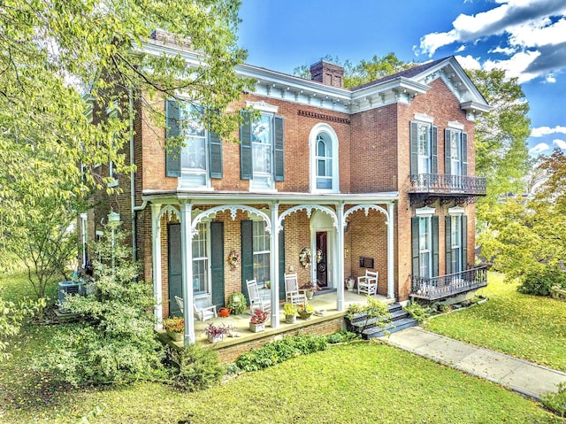 italianate house with a front yard, a porch, brick siding, and a chimney