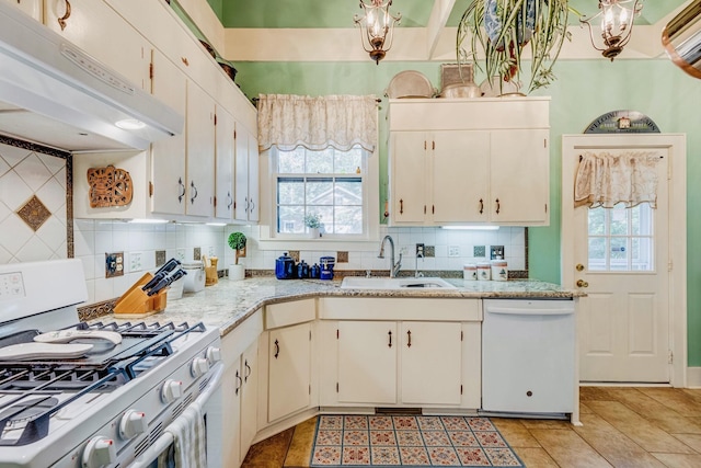 kitchen with white appliances, a healthy amount of sunlight, under cabinet range hood, and a sink