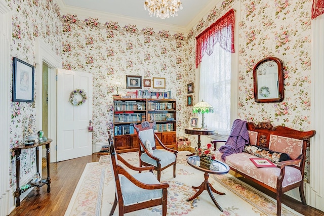 living area featuring wallpapered walls, an inviting chandelier, wood finished floors, and ornamental molding