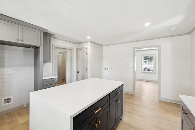 kitchen with light wood-type flooring, gray cabinetry, a kitchen island, a textured ceiling, and light countertops