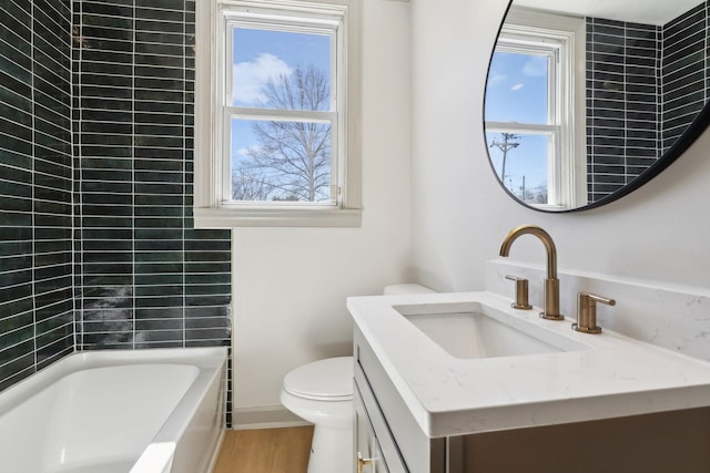 bathroom featuring toilet, wood finished floors, plenty of natural light, and vanity