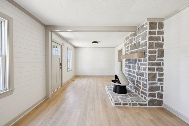 foyer with baseboards, a textured ceiling, light wood-style flooring, and crown molding