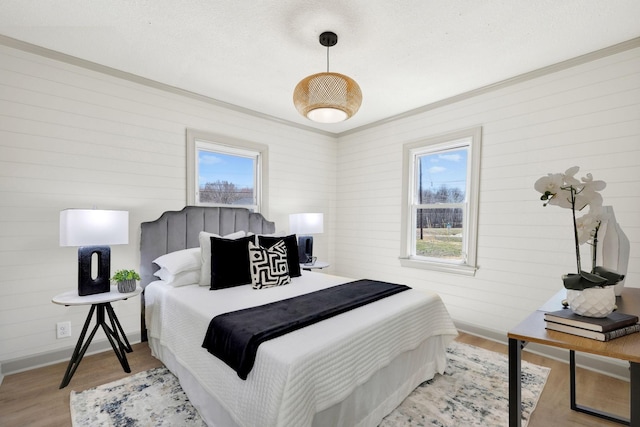 bedroom with ornamental molding, baseboards, and wood finished floors