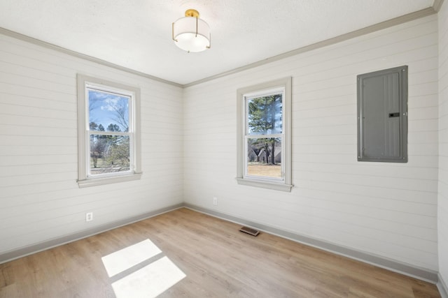 spare room featuring visible vents, baseboards, electric panel, wood finished floors, and a textured ceiling