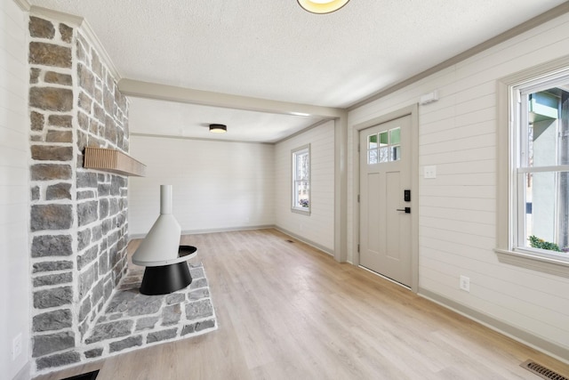 entrance foyer featuring visible vents, a textured ceiling, baseboards, and wood finished floors