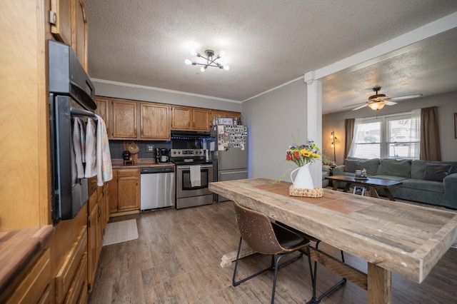 kitchen featuring ventilation hood, brown cabinets, appliances with stainless steel finishes, wood finished floors, and a textured ceiling