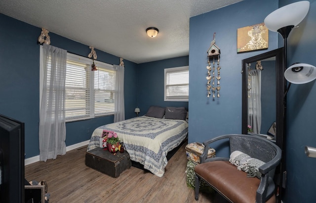 bedroom with a textured ceiling, baseboards, and wood finished floors