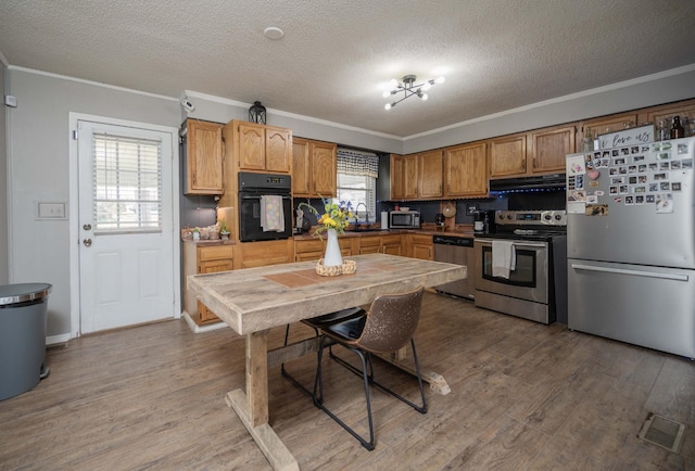 kitchen featuring range hood, appliances with stainless steel finishes, wood finished floors, and ornamental molding