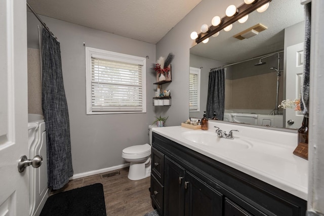 full bath with vanity, wood finished floors, visible vents, and a textured ceiling