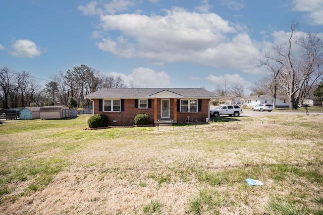 view of front of home featuring an outbuilding, brick siding, a storage shed, and a front lawn