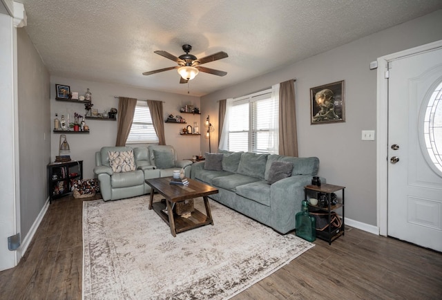 living room with a ceiling fan, dark wood-style flooring, and a textured ceiling