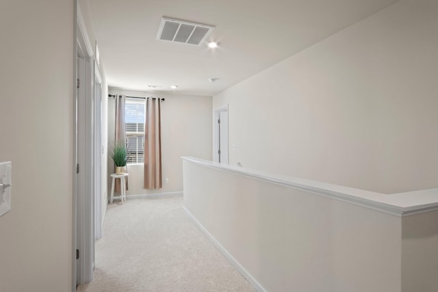 corridor with visible vents, light carpet, and baseboards