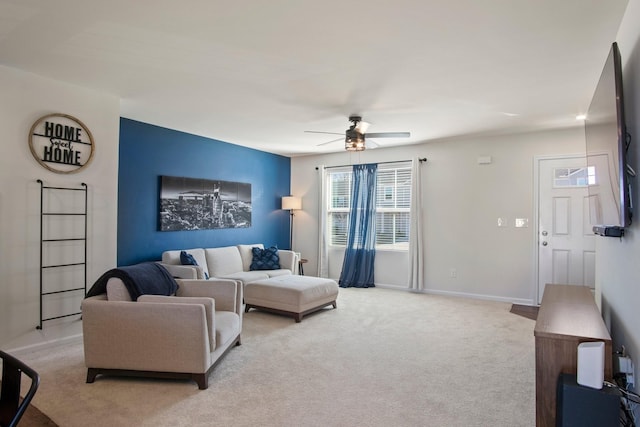 living room featuring baseboards, light colored carpet, and ceiling fan