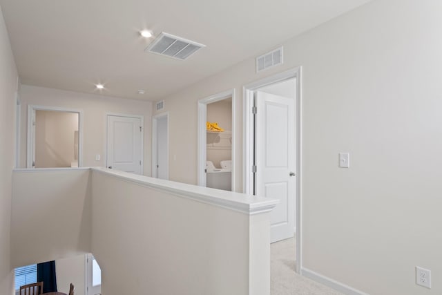 corridor featuring carpet flooring, an upstairs landing, visible vents, and washing machine and clothes dryer