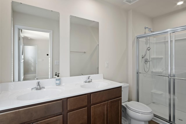 bathroom featuring double vanity, a stall shower, toilet, and a sink