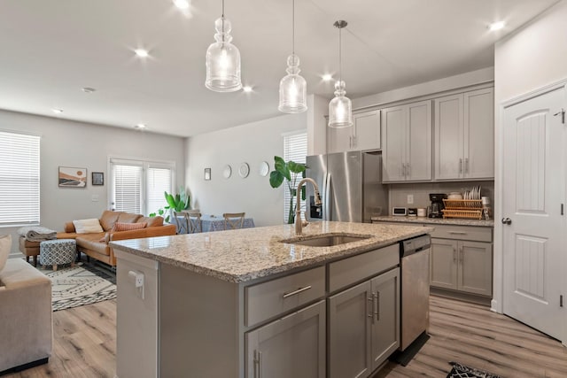 kitchen featuring open floor plan, gray cabinets, appliances with stainless steel finishes, wood finished floors, and a sink