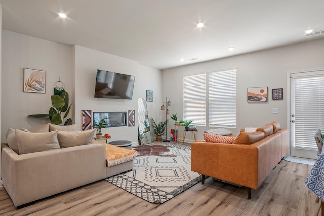 living room with recessed lighting, visible vents, light wood-type flooring, and baseboards