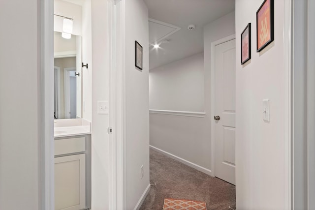 corridor featuring attic access, baseboards, and carpet floors