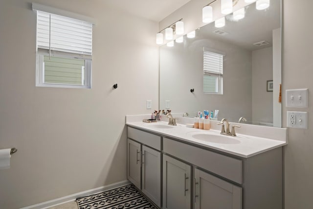 bathroom with a sink, visible vents, baseboards, and double vanity