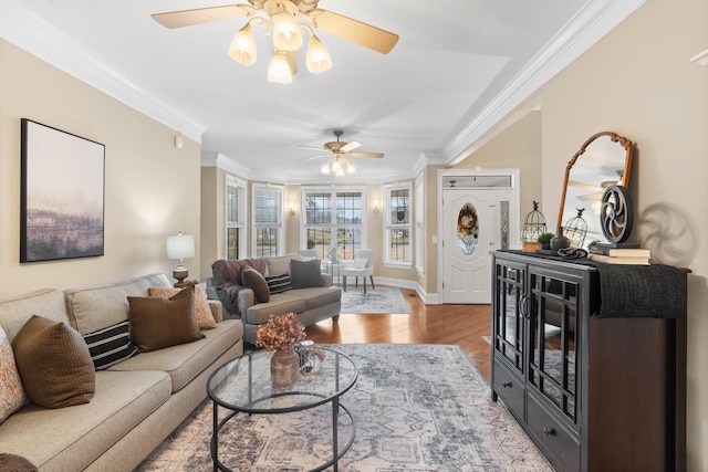 living area featuring baseboards, wood finished floors, ceiling fan, and ornamental molding