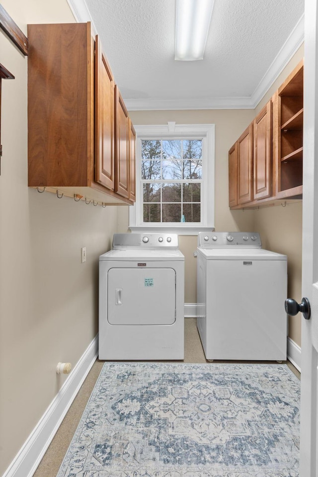 clothes washing area with a textured ceiling, baseboards, separate washer and dryer, cabinet space, and light carpet