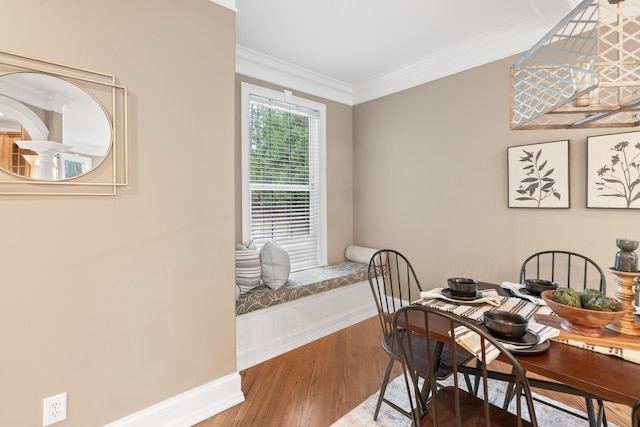 dining room featuring baseboards, wood finished floors, and ornamental molding