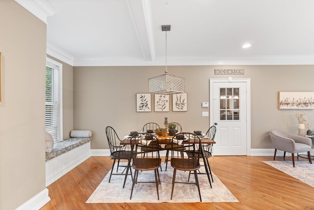 dining space with baseboards, beam ceiling, crown molding, and light wood finished floors