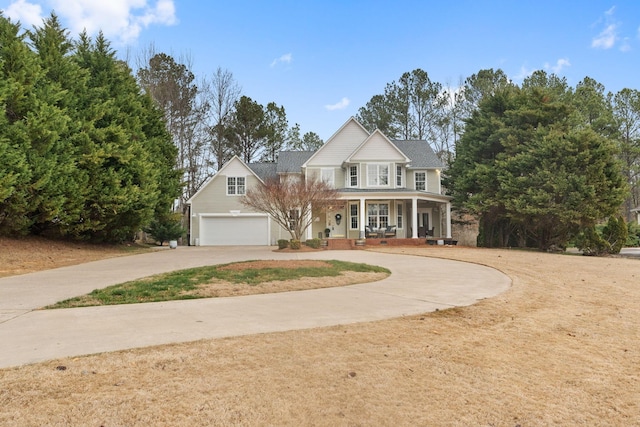 view of front of property with a garage, curved driveway, and covered porch