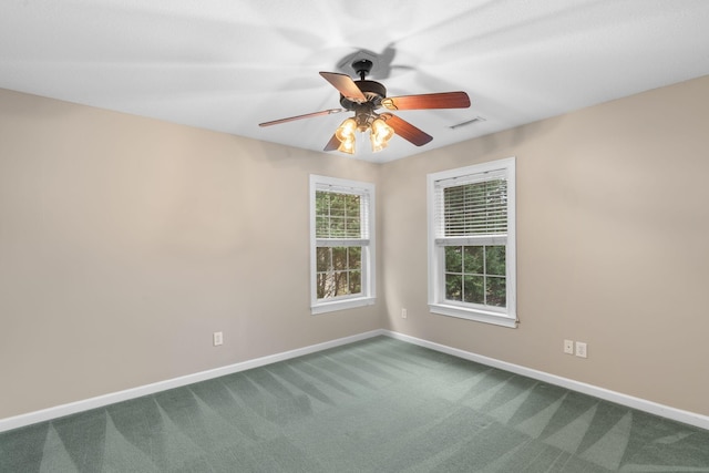 unfurnished room with dark colored carpet, visible vents, baseboards, and a ceiling fan