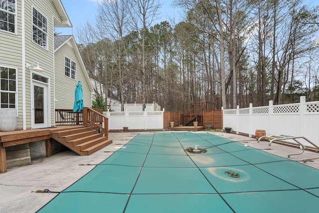 view of swimming pool featuring a wooden deck, a patio area, a fenced in pool, and fence