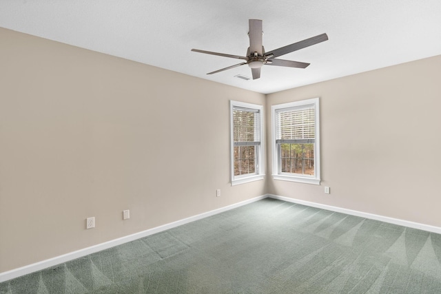 spare room with baseboards, dark carpet, and a ceiling fan