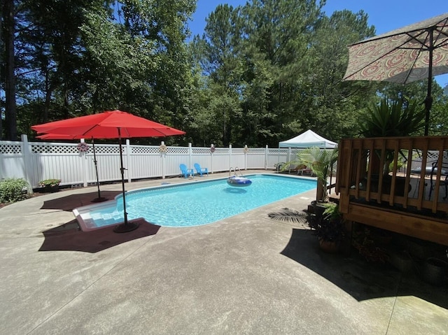 view of pool with a fenced in pool, a patio, a wooden deck, and a fenced backyard