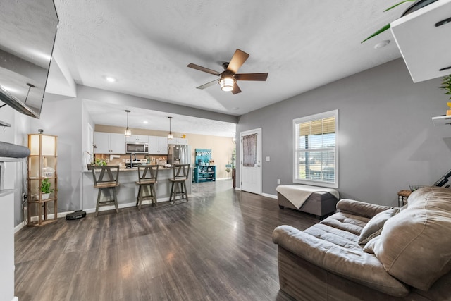 living area with a textured ceiling, dark wood-style floors, recessed lighting, baseboards, and ceiling fan