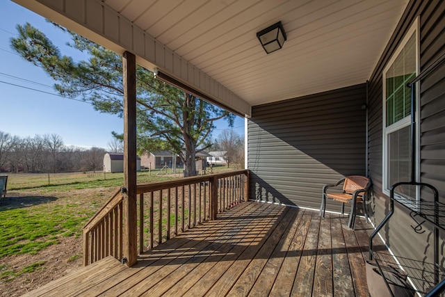 wooden terrace with an outbuilding, a storage shed, and a lawn