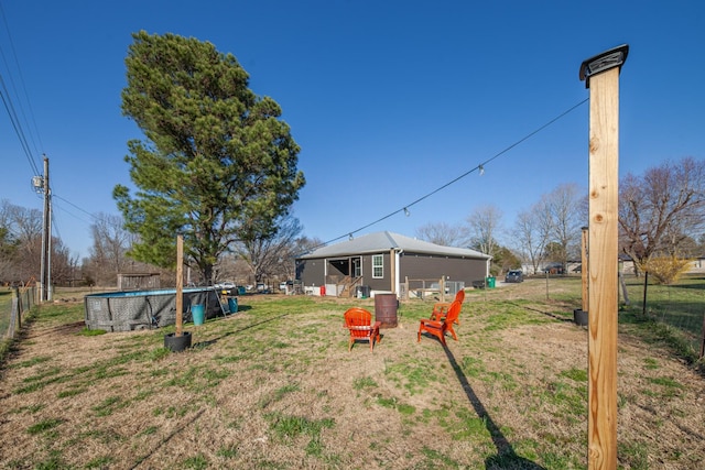 view of yard featuring an outdoor pool, an outbuilding, and fence