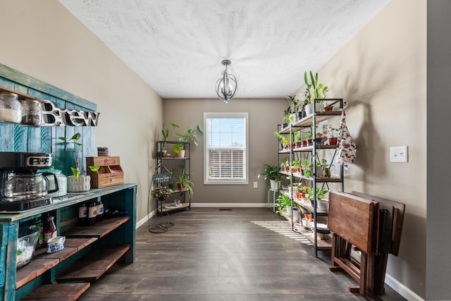 interior space featuring baseboards, a textured ceiling, an inviting chandelier, and wood finished floors