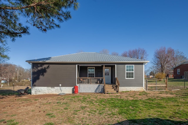 view of front of home featuring metal roof, covered porch, a front yard, and fence