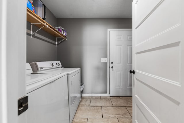 laundry area featuring washing machine and clothes dryer, laundry area, baseboards, and light tile patterned floors