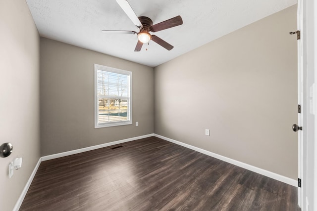 empty room with dark wood finished floors, visible vents, baseboards, and ceiling fan