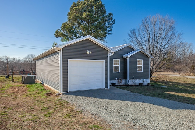 view of front of property featuring gravel driveway, a garage, and central AC