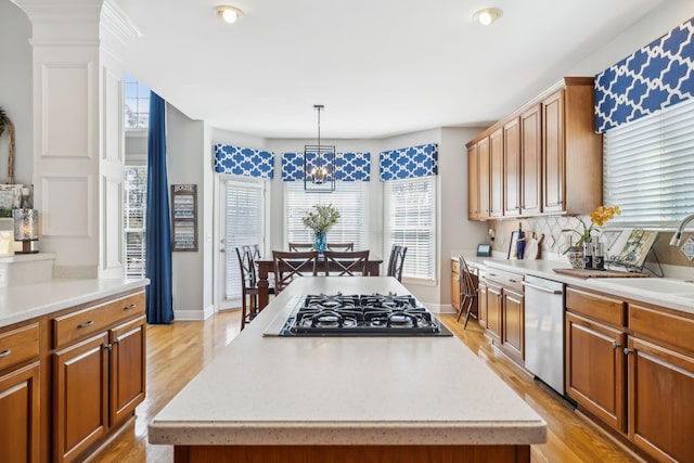 kitchen with a sink, gas cooktop, stainless steel dishwasher, and light countertops