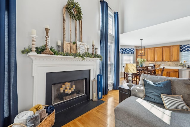 living room featuring a fireplace with flush hearth, a high ceiling, and light wood-style flooring