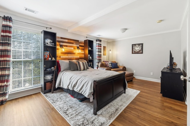 bedroom with crown molding, wood finished floors, and visible vents